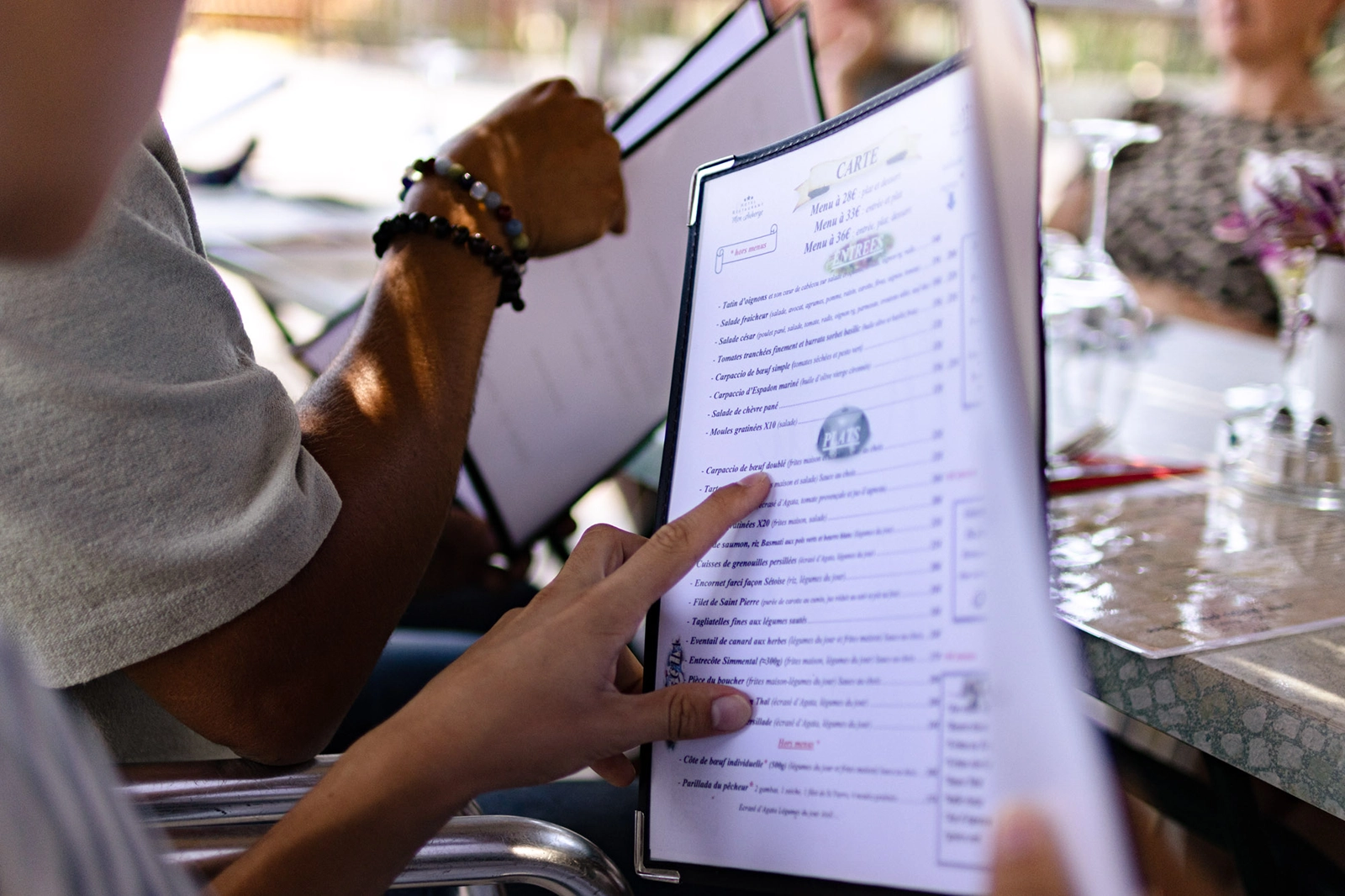 Clients pointant un plat sur la carte de menu du restaurant Mon Auberge